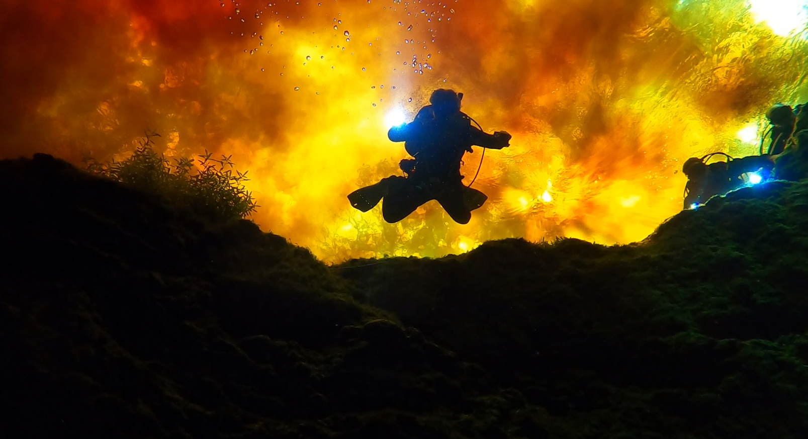 Diver looking down from above with water mixing above that looks like fire
